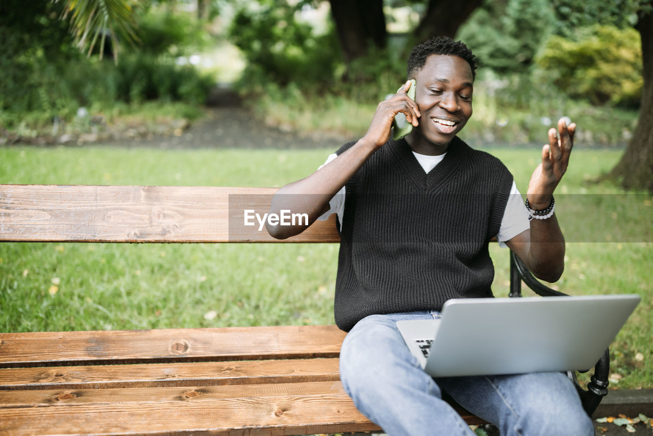 portrait of young woman using laptop while sitting on bench