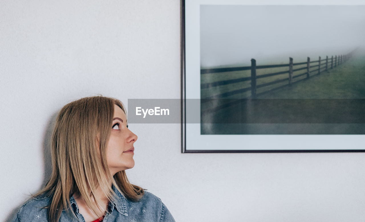 Woman looking at frame against wall