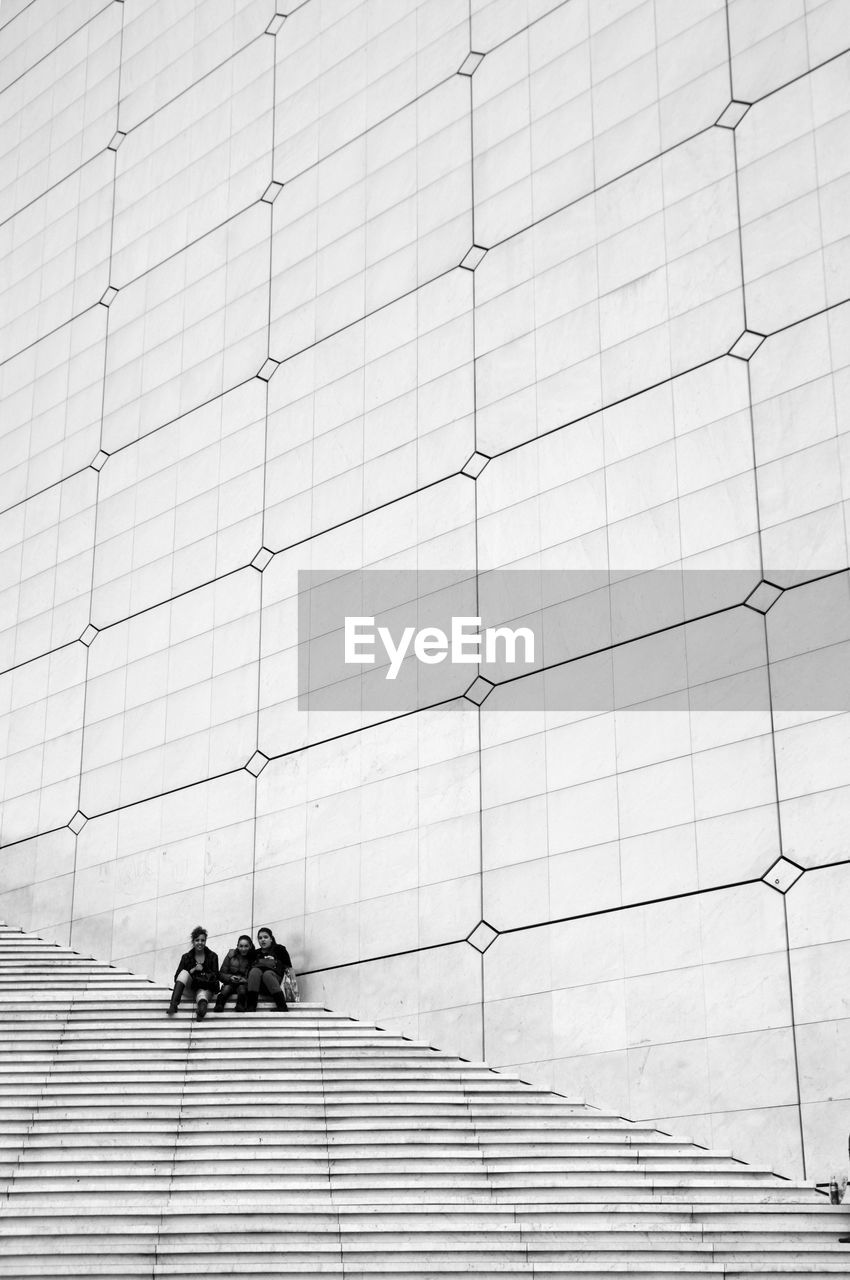 People sitting on staircase against wall