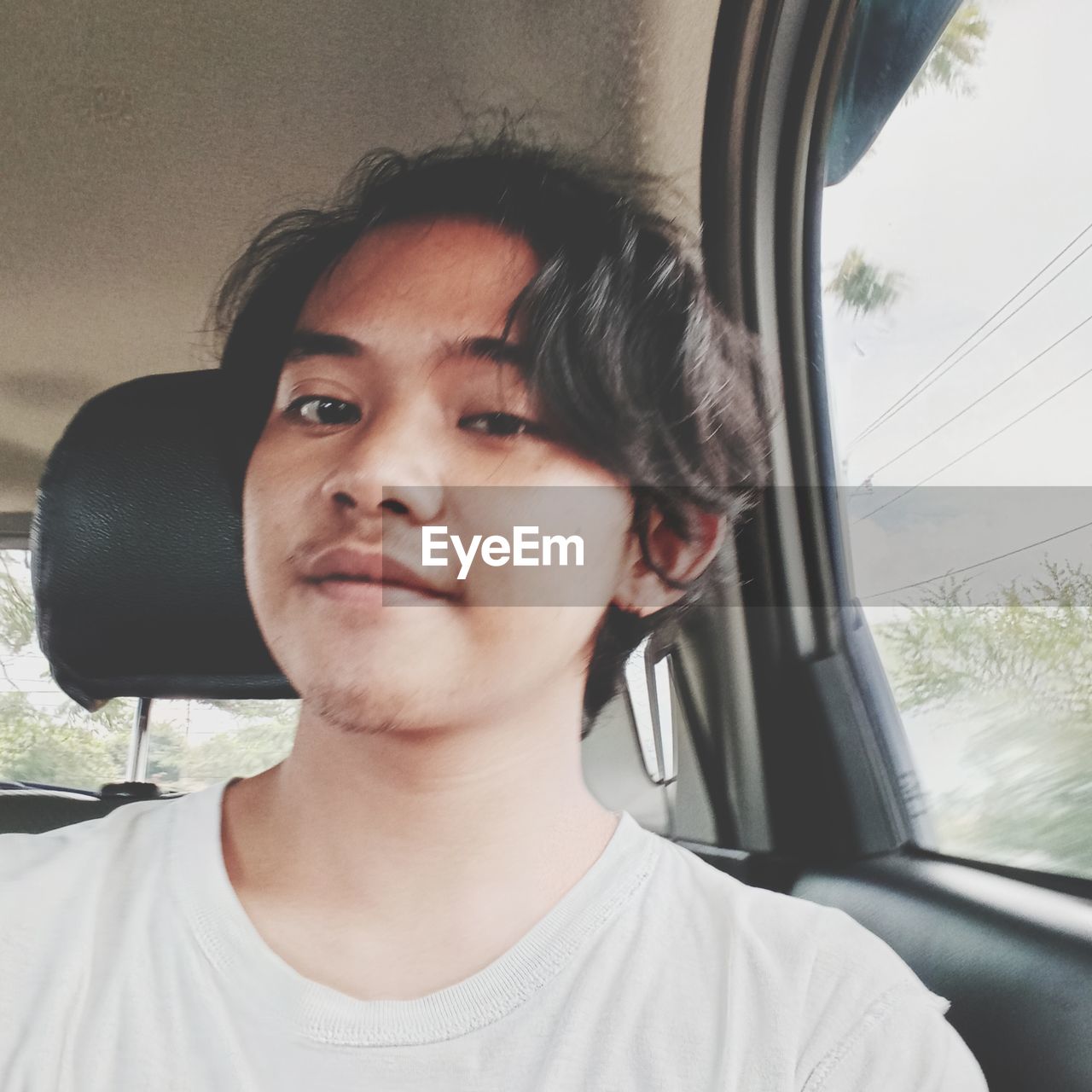 PORTRAIT OF YOUNG MAN WITH CAR IN BACKGROUND