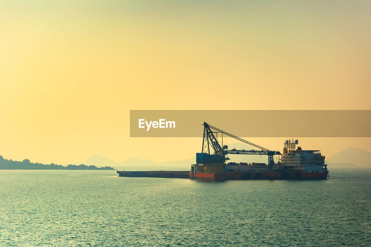 CRANE AT COMMERCIAL DOCK AGAINST CLEAR SKY