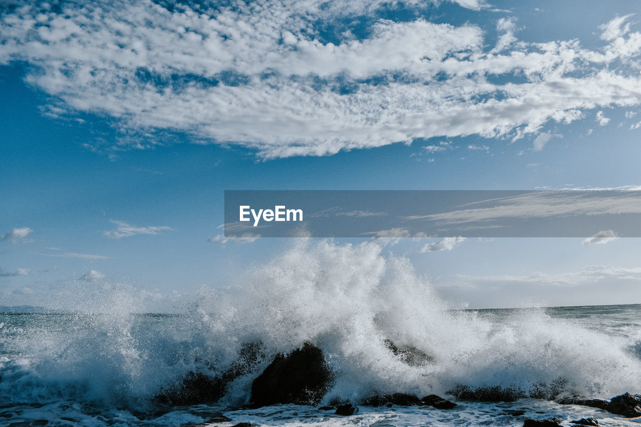 Waves splashing on shore against sky