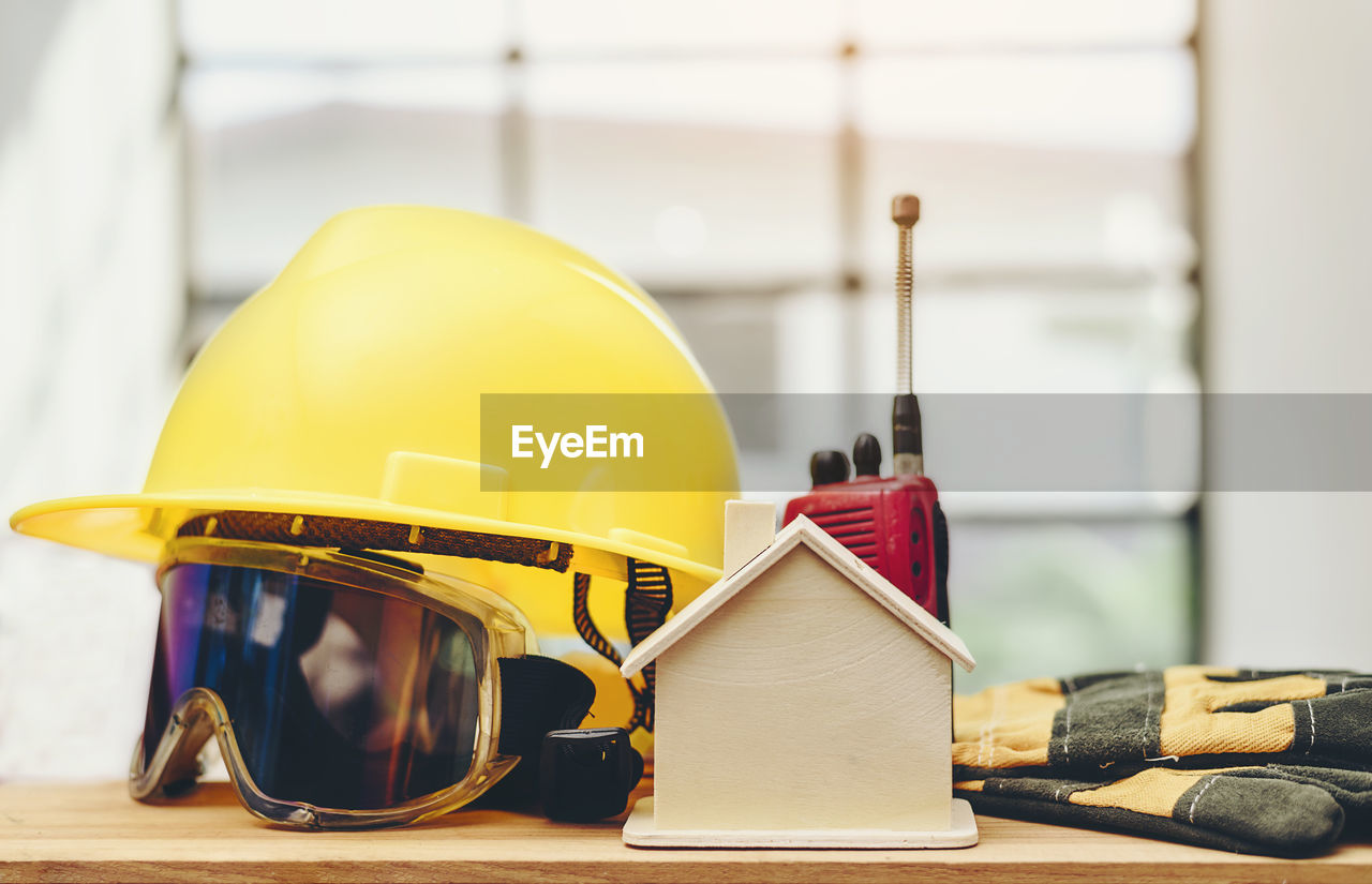 Close-up of protective workwear with walkie-talkie by model home on table