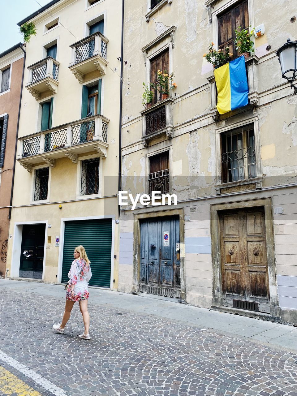 Rear view of woman walking on street and ukrainian flag on window 