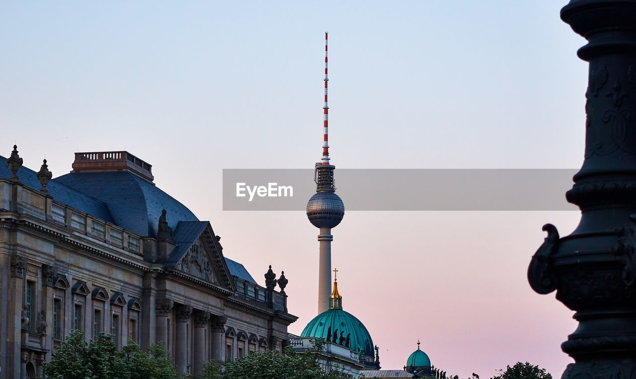 Communications tower in city against clear sky