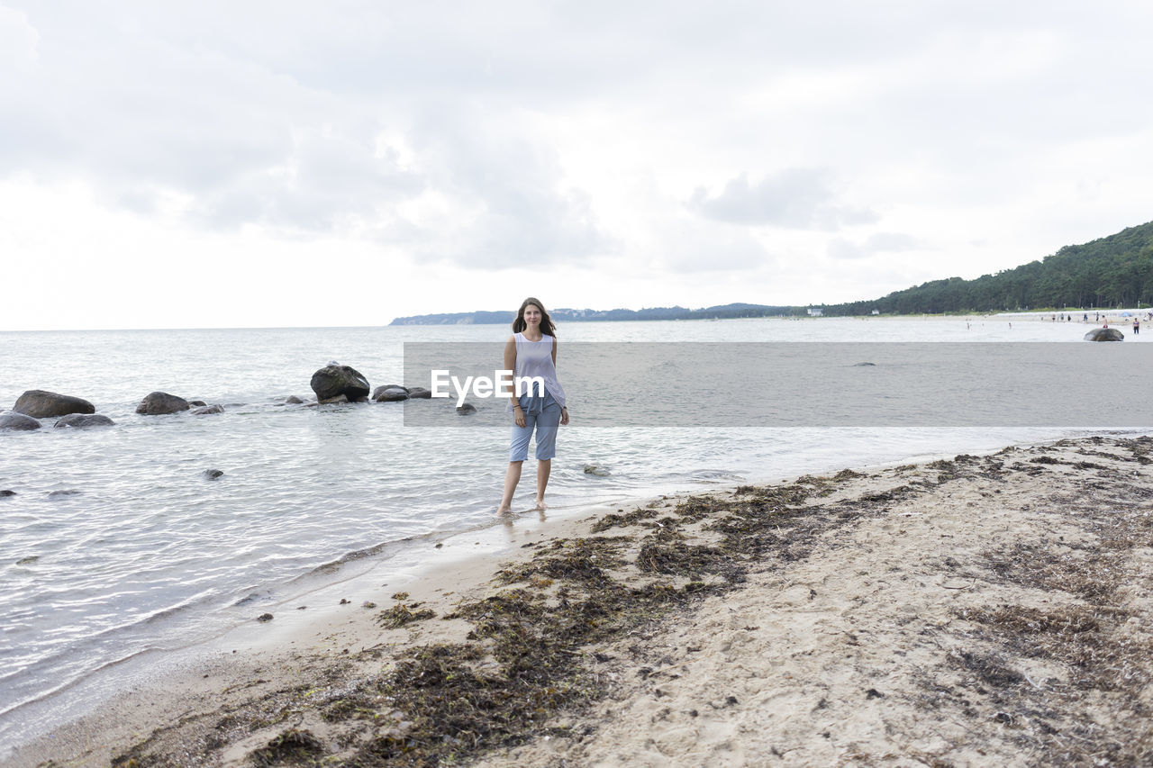 Woman standing at beach against sky