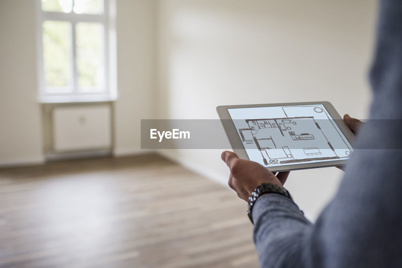 Man in new home holding tablet with floor plan