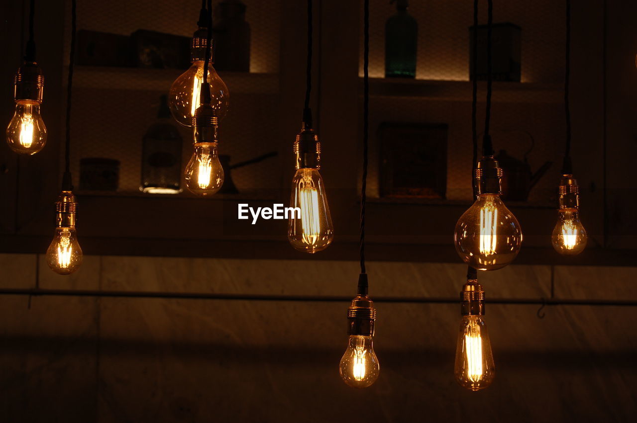 LOW ANGLE VIEW OF ILLUMINATED LIGHTING EQUIPMENT HANGING ON CEILING