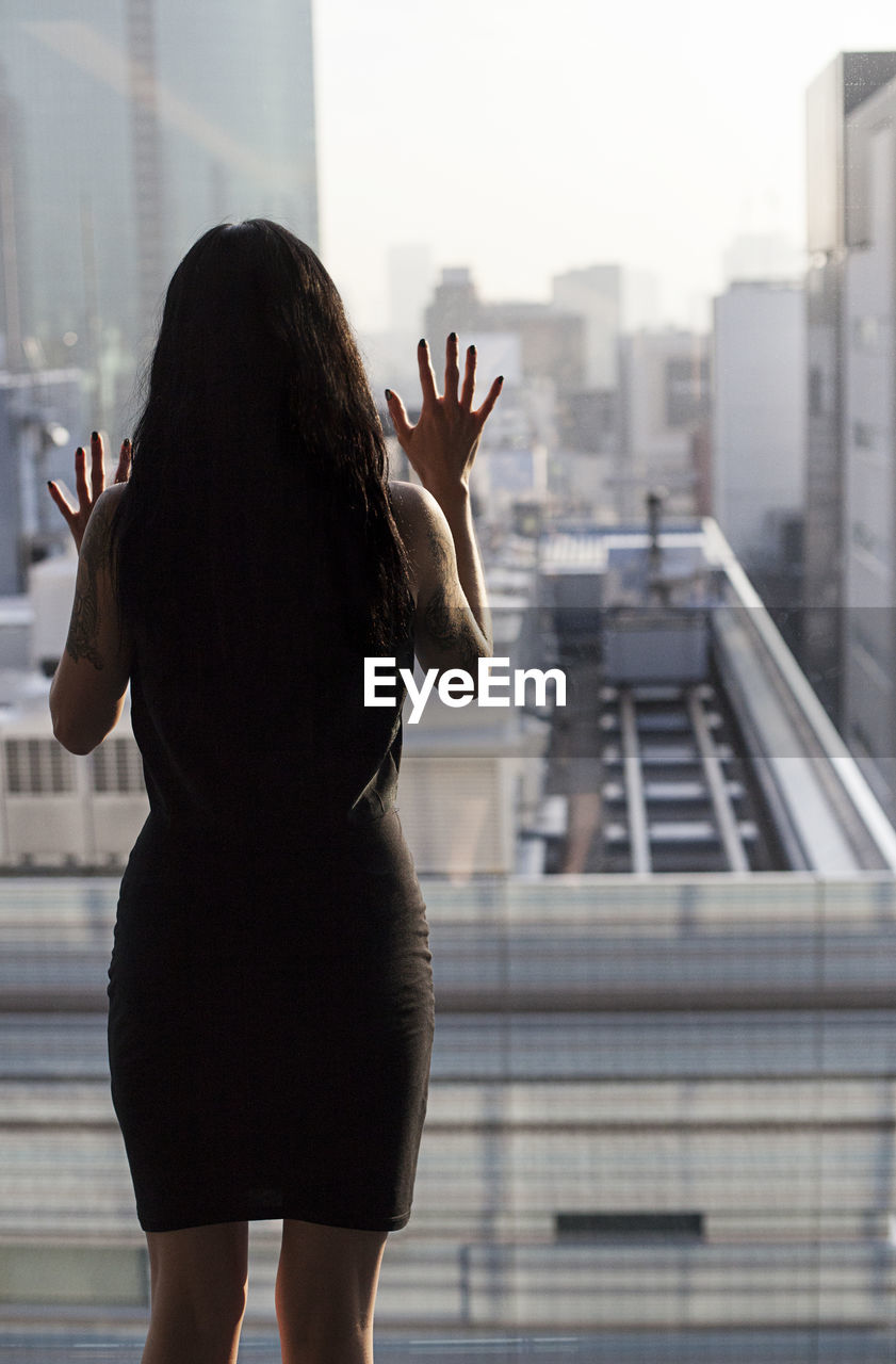 Rear view of woman looking through window