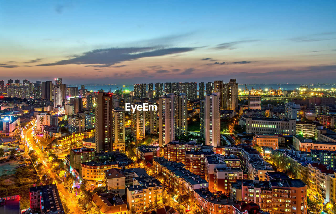 Illuminated cityscape against sky at dusk