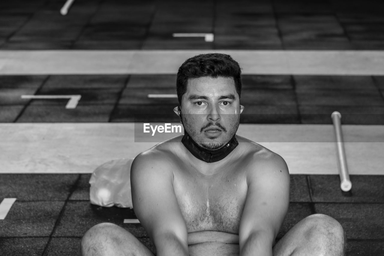 Portrait of young man sitting in swimming pool