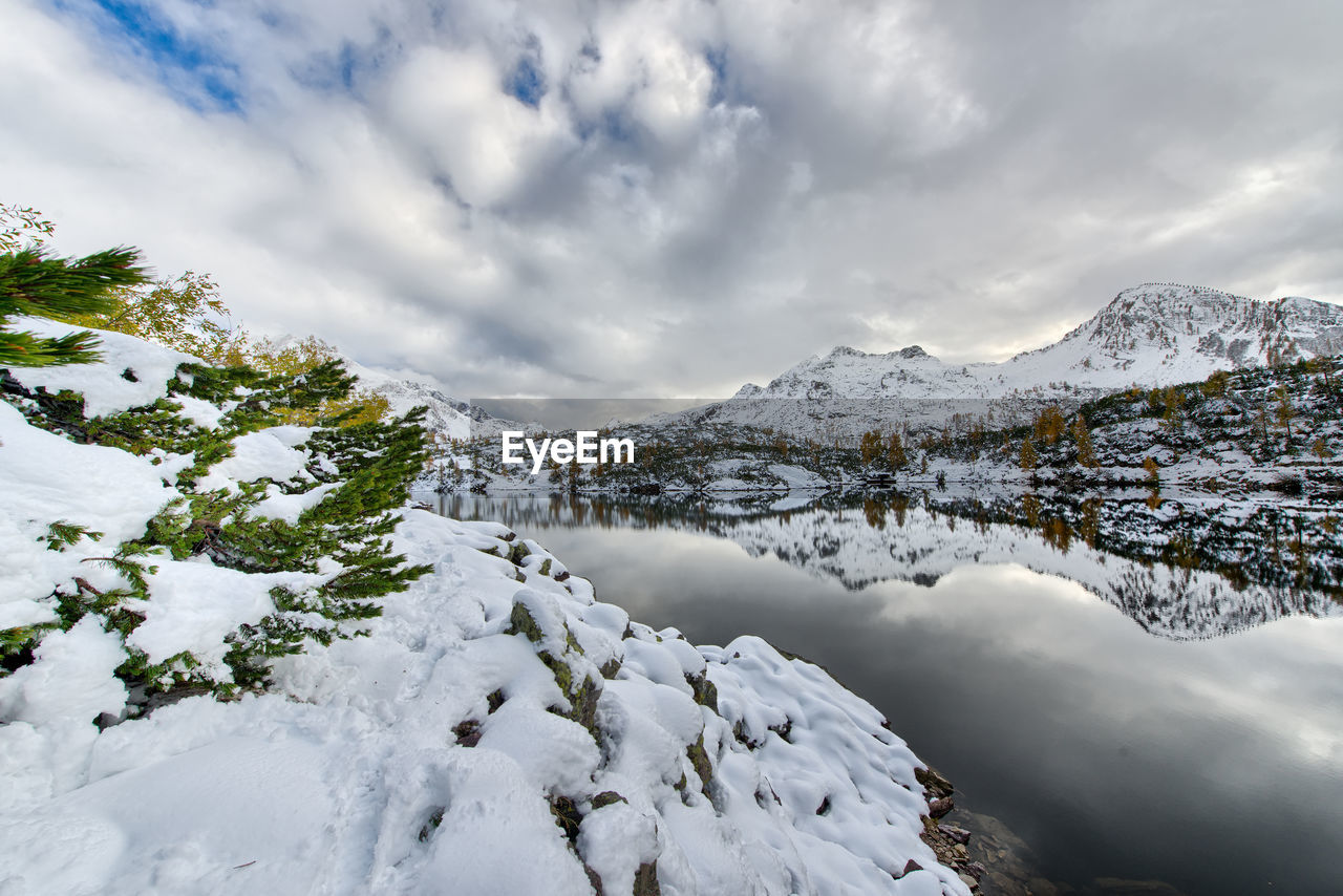 Walking beside alpine lake with snow in the autumn