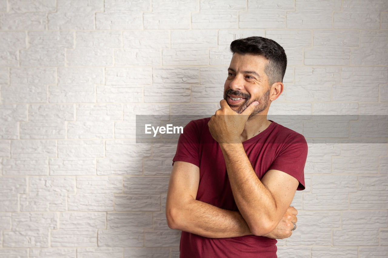 SMILING YOUNG MAN STANDING BY WALL