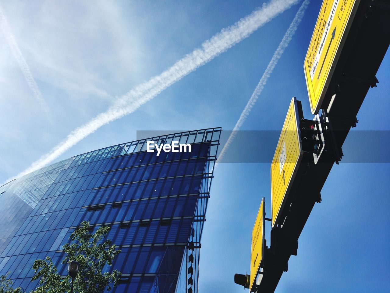 Low angle view of building against vapor trail in sky