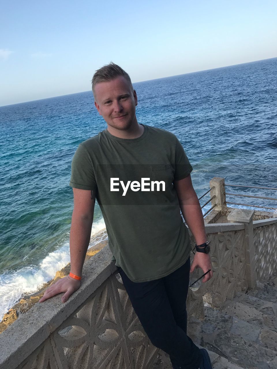 Portrait of man standing on steps against sea