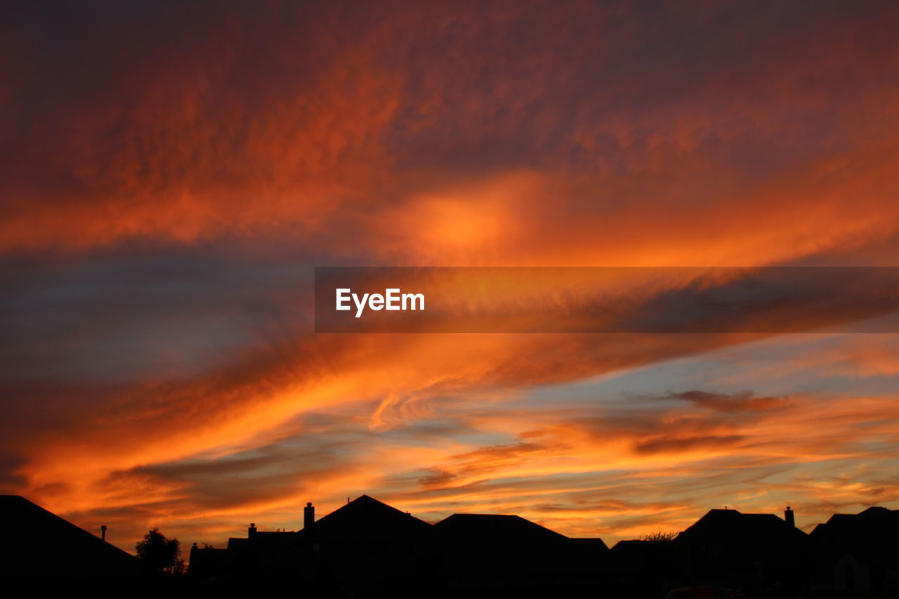 Silhouette buildings against orange sky