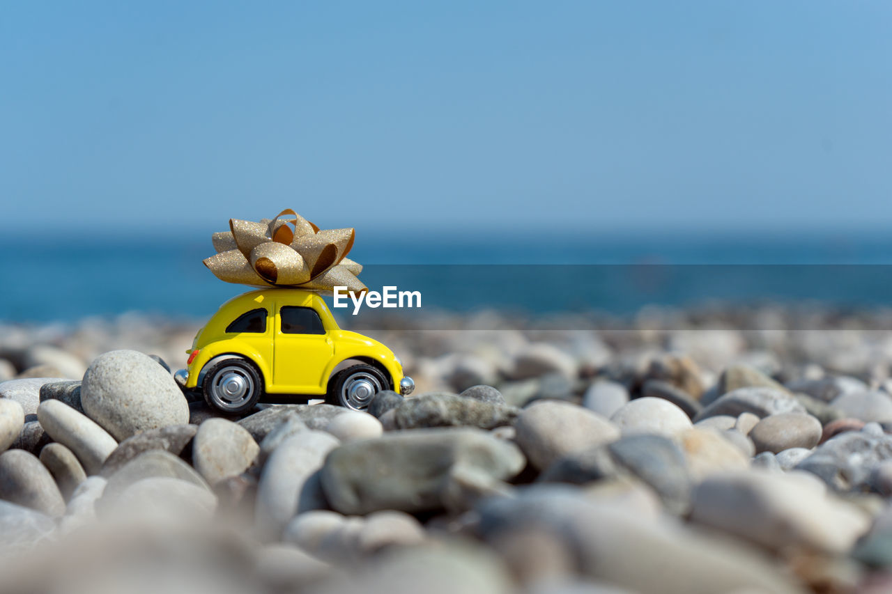 CLOSE-UP OF YELLOW TOY ON SHORE