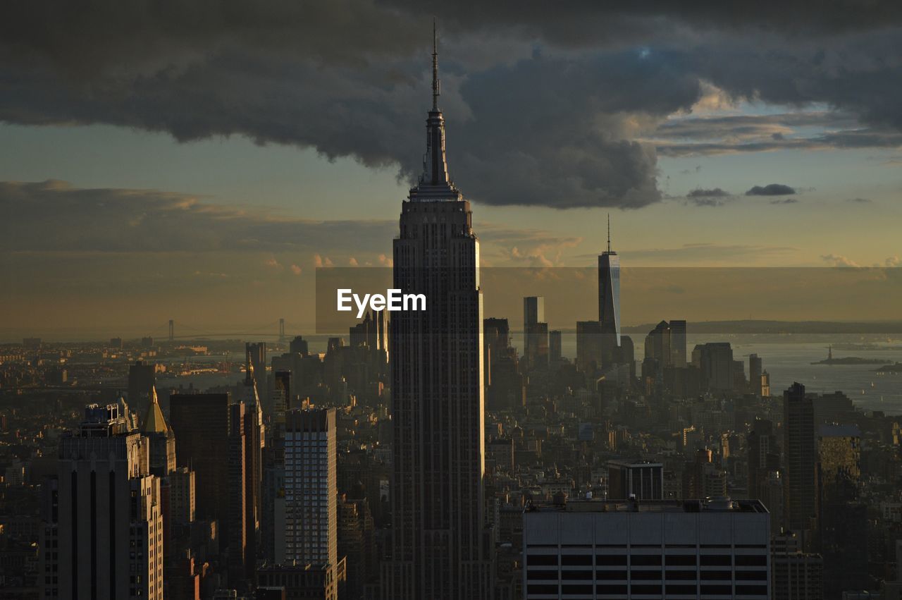 Modern buildings in city against sky during sunset