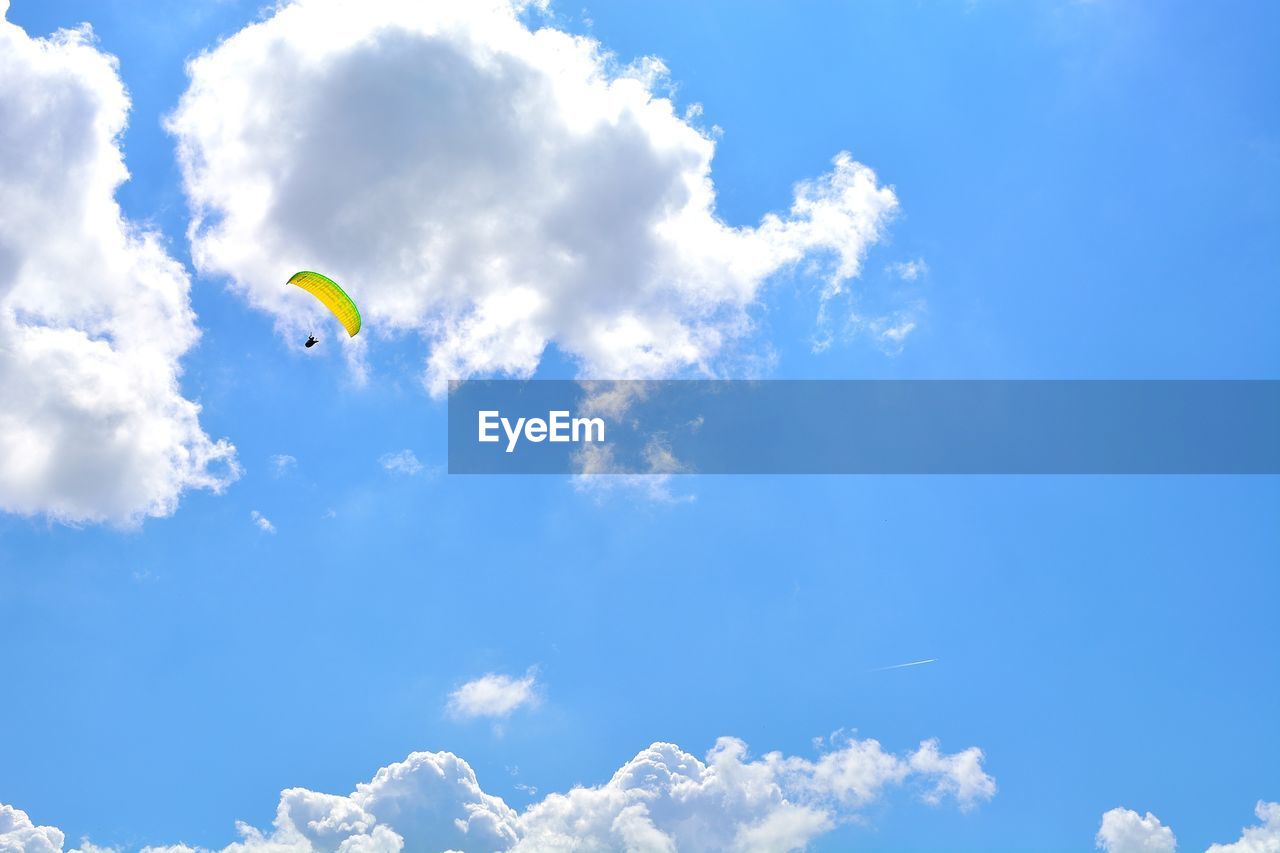 Low angle view of person paragliding against blue sky