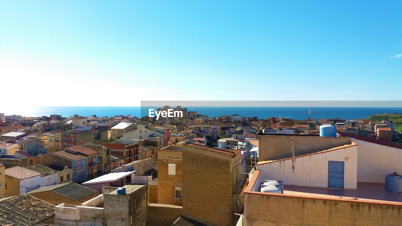 High angle view of townscape by sea against clear sky