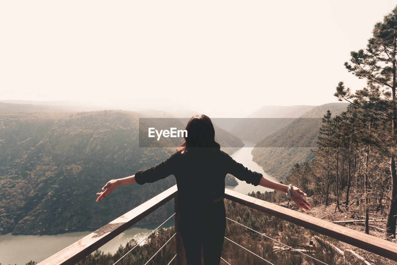 REAR VIEW OF MAN LOOKING AT MOUNTAINS