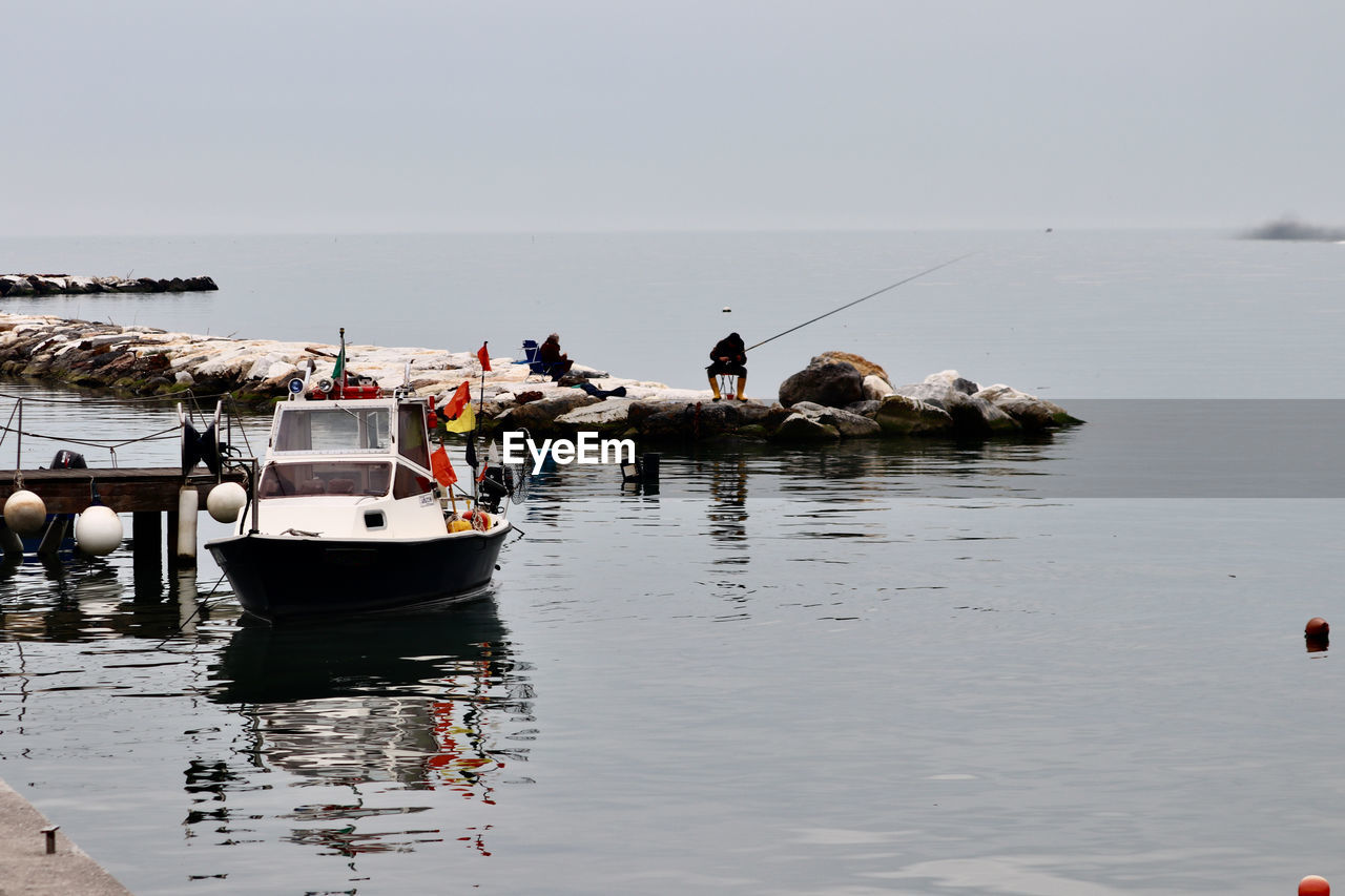 BOAT MOORED IN SEA AGAINST CLEAR SKY