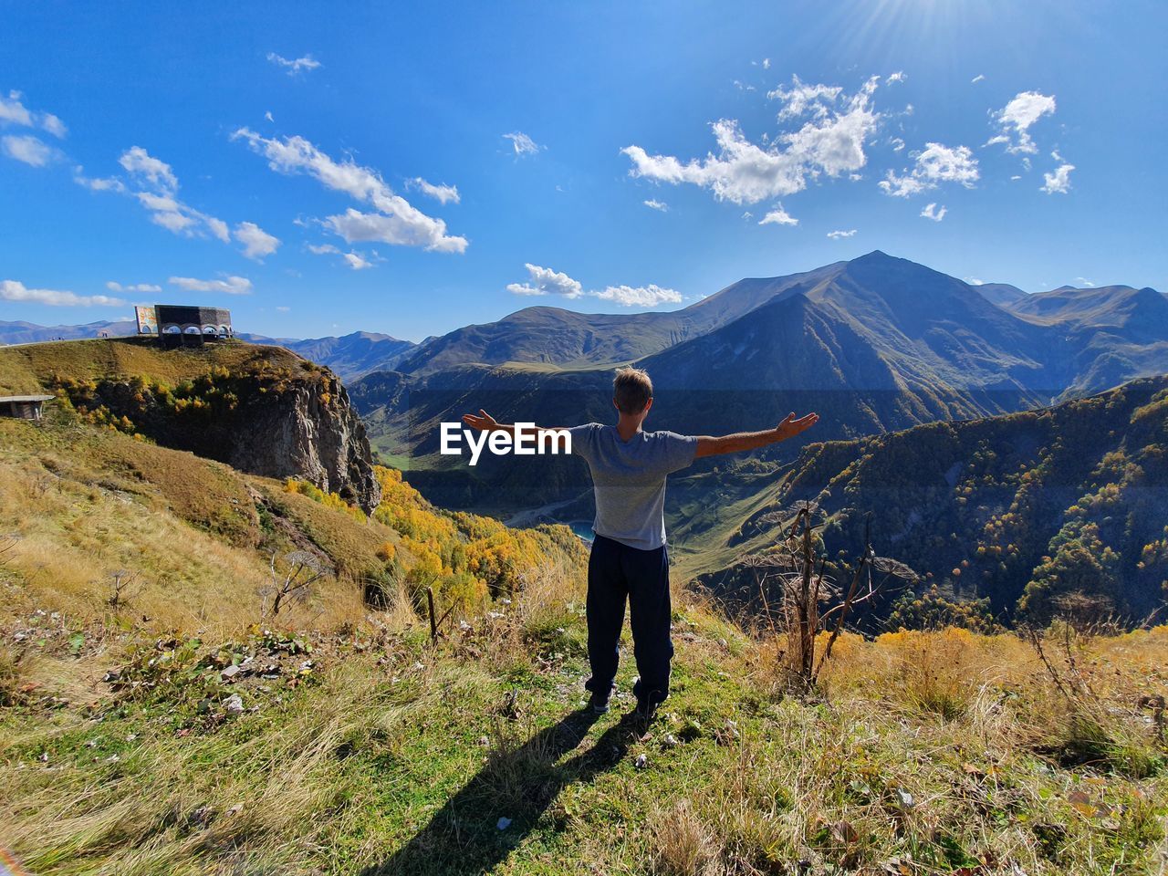 Rear view of man standing on mountain against sky