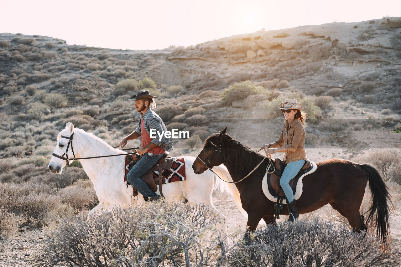 Young people riding horses doing excursion at sunset 