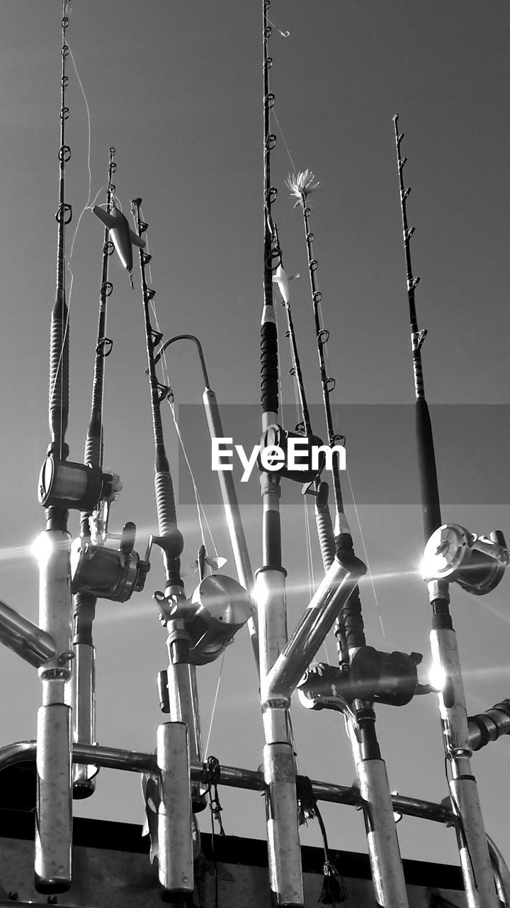 Low angle view of fishing rods  hanging against sky