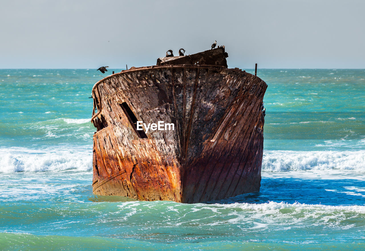 Ship wreck on sea shore against sky