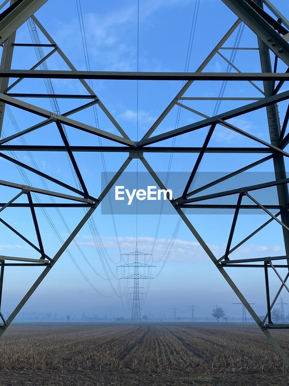 Electricity pylon on field against sky