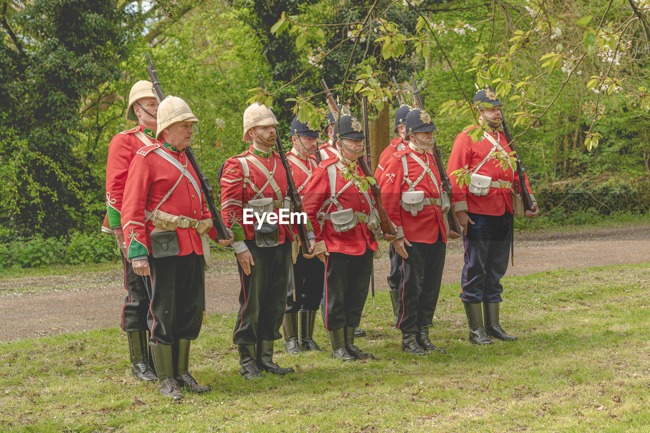 group of people, clothing, full length, plant, men, nature, day, tree, adult, standing, uniform, togetherness, women, outdoors, cooperation, teamwork, hat, grass, musical instrument, person
