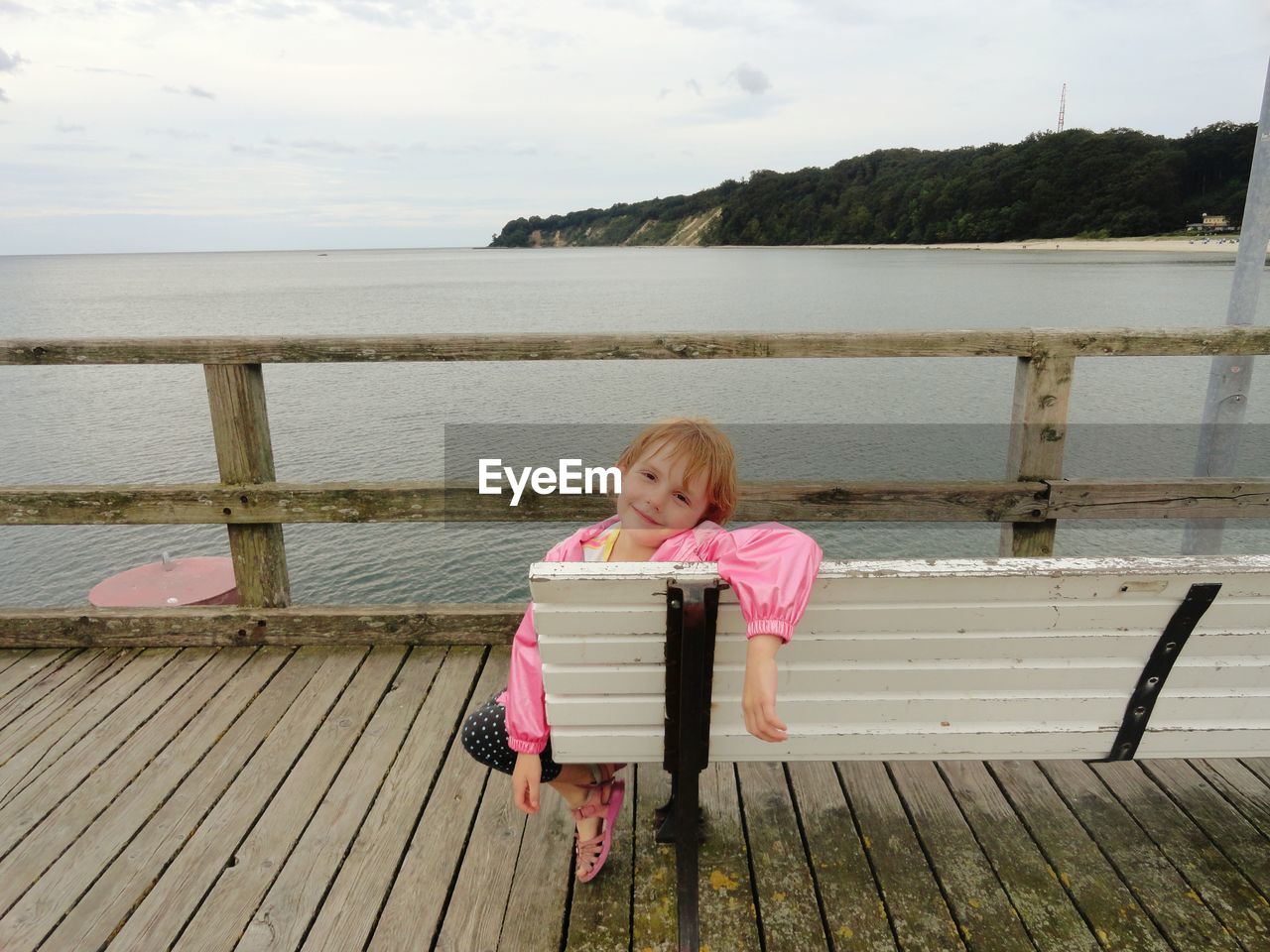 Full length of girl sitting on a bench by a beach in rügen, germany, baltic sea 