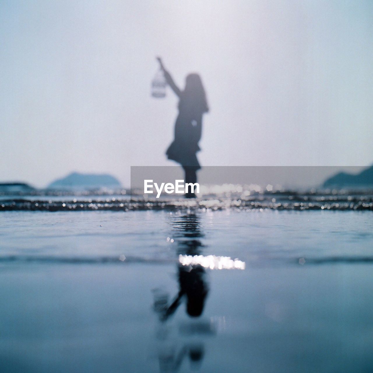 Water surface of woman standing in sea against clear sky during sunny day