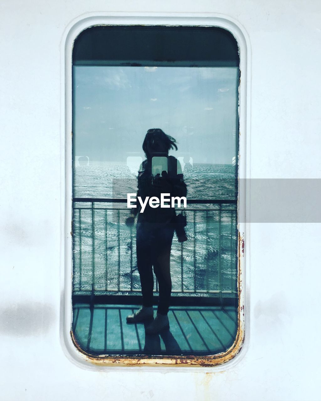 Woman overlooking calm sea against the sky