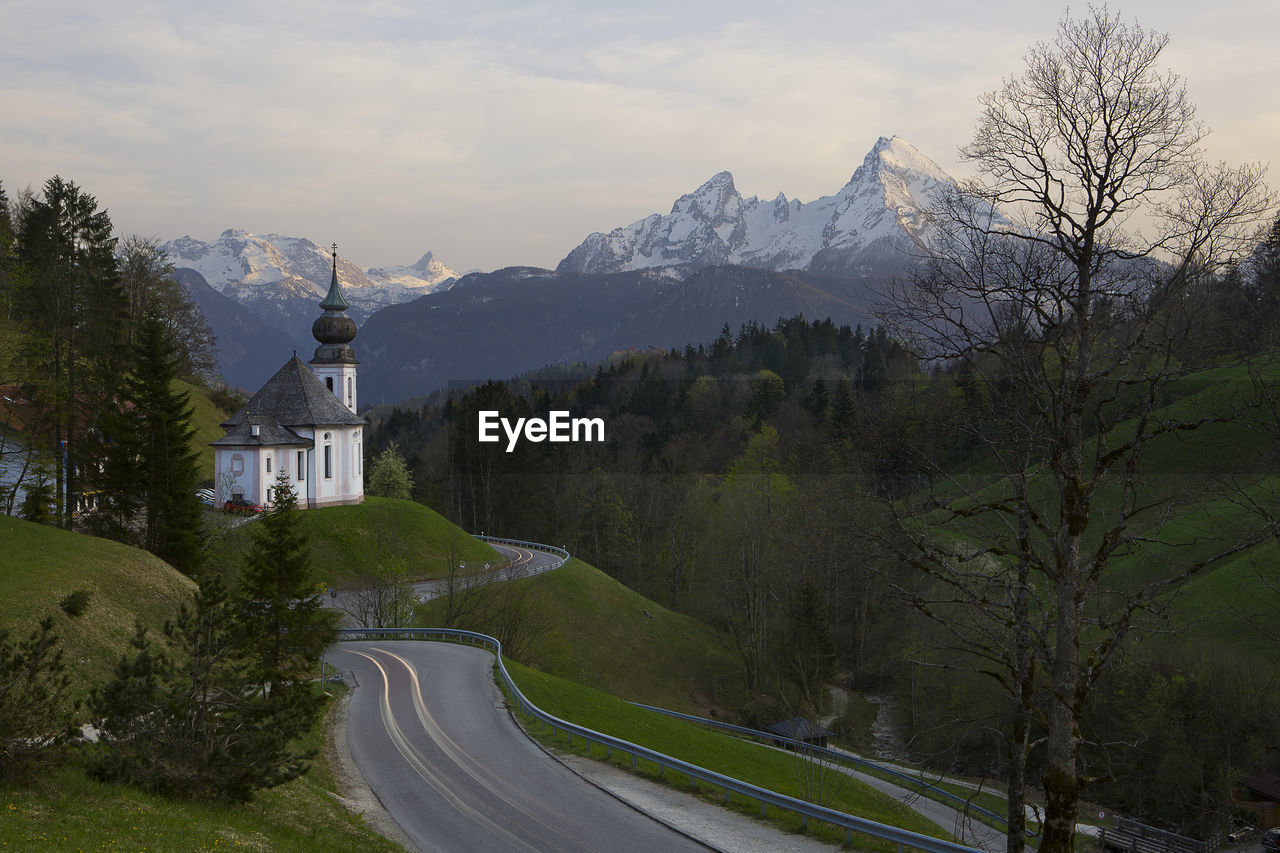 Road amidst trees and mountains against sky