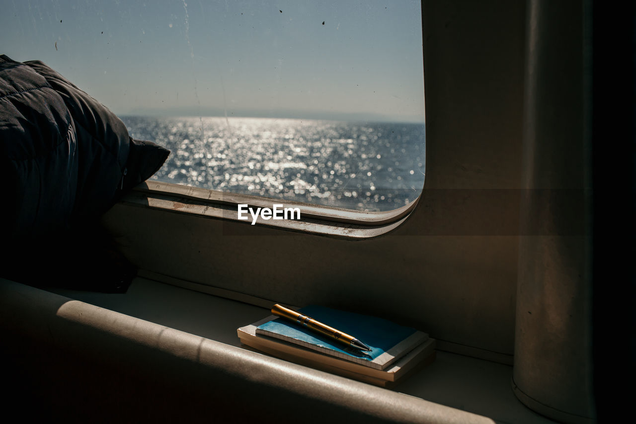 Close-up of books with pen by window in ship
