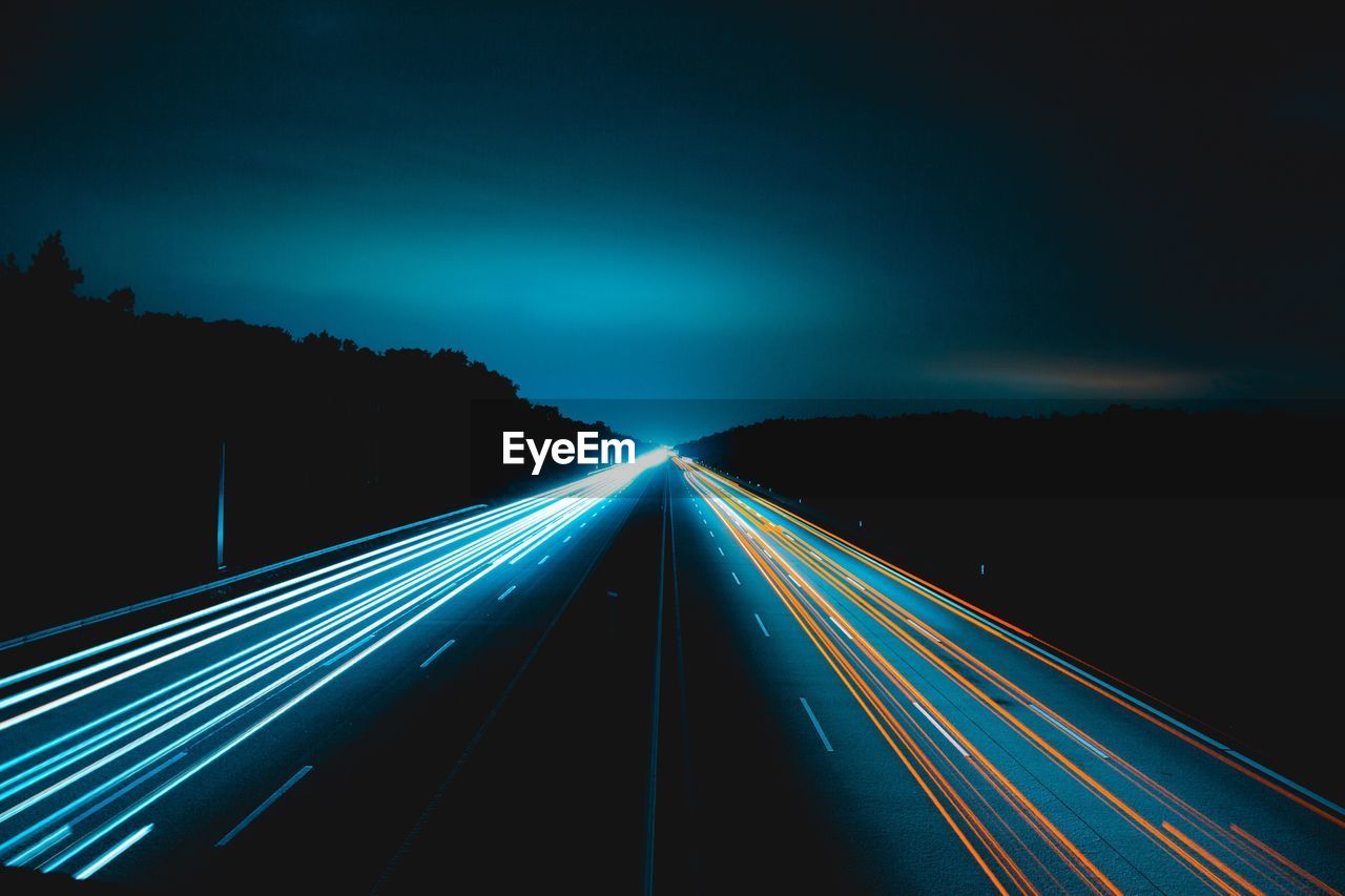 Light trails on road against sky at night