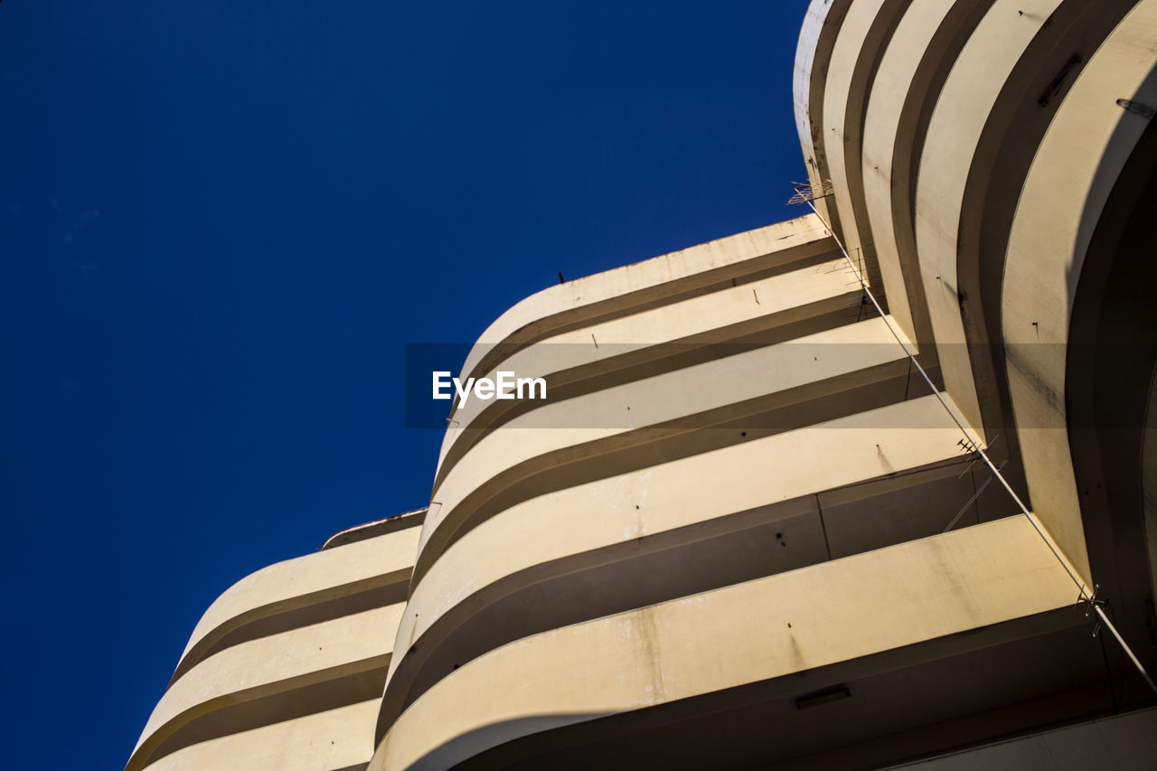 LOW ANGLE VIEW OF MODERN BUILDING AGAINST CLEAR BLUE SKY