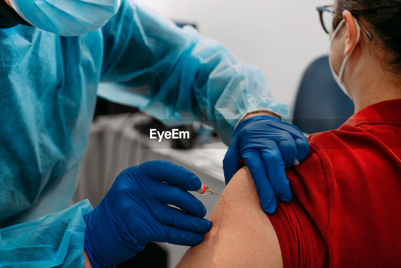 Low section of doctor giving vaccine injection to patient