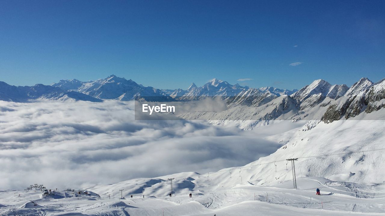 Scenic view of snow covered mountains against clear blue sky