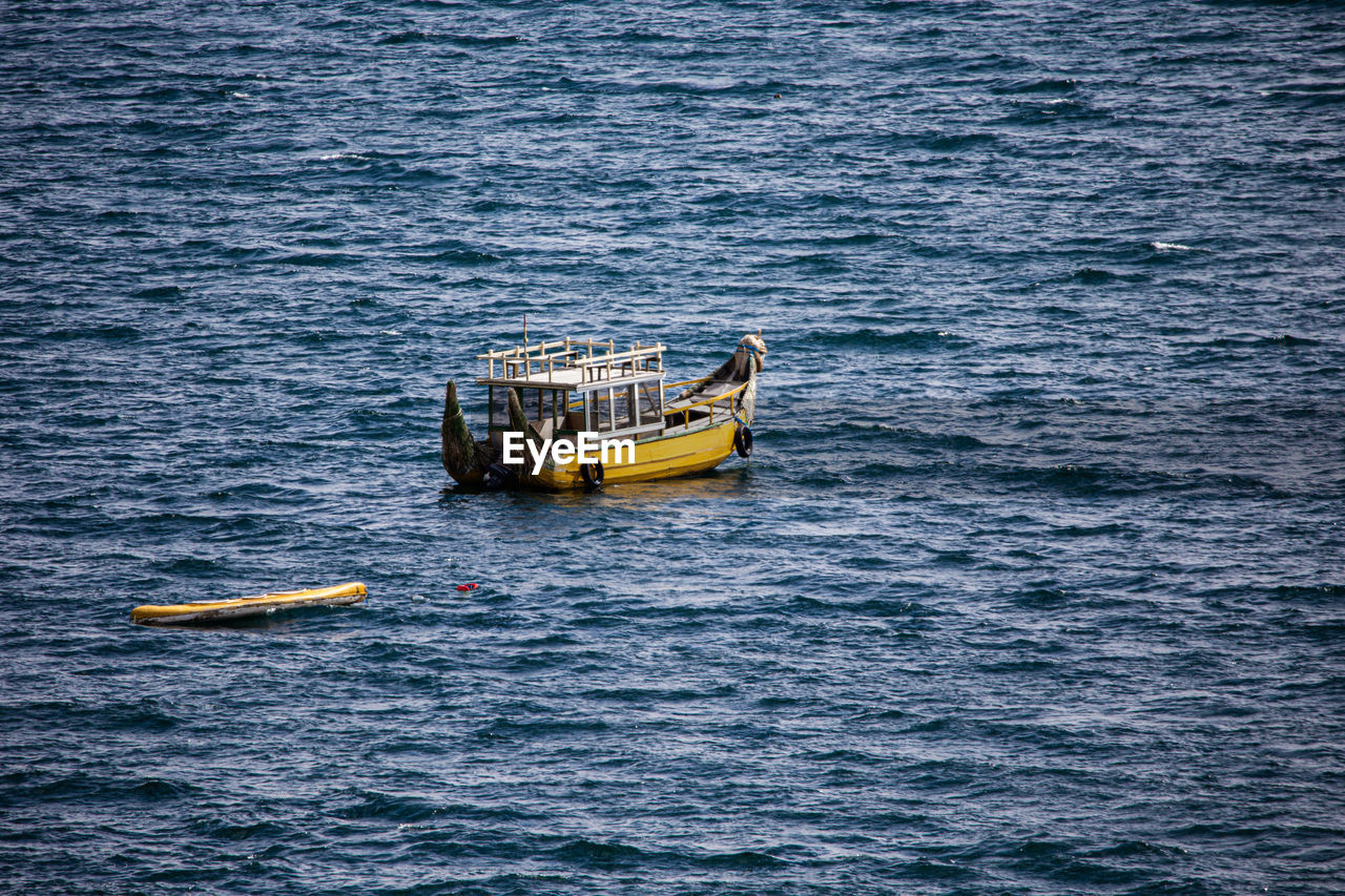 HIGH ANGLE VIEW OF SAILBOAT SAILING IN SEA