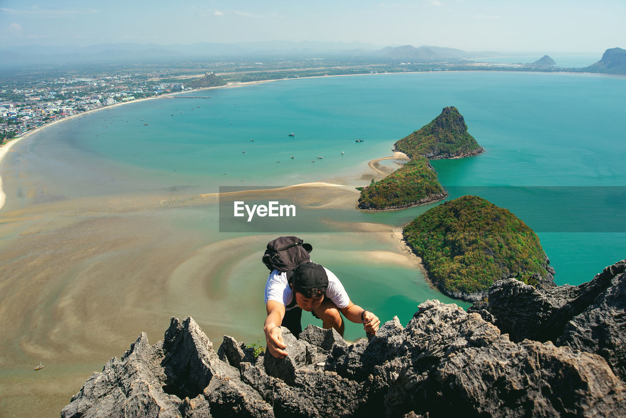 High angle view of man climbing on mountain against sea