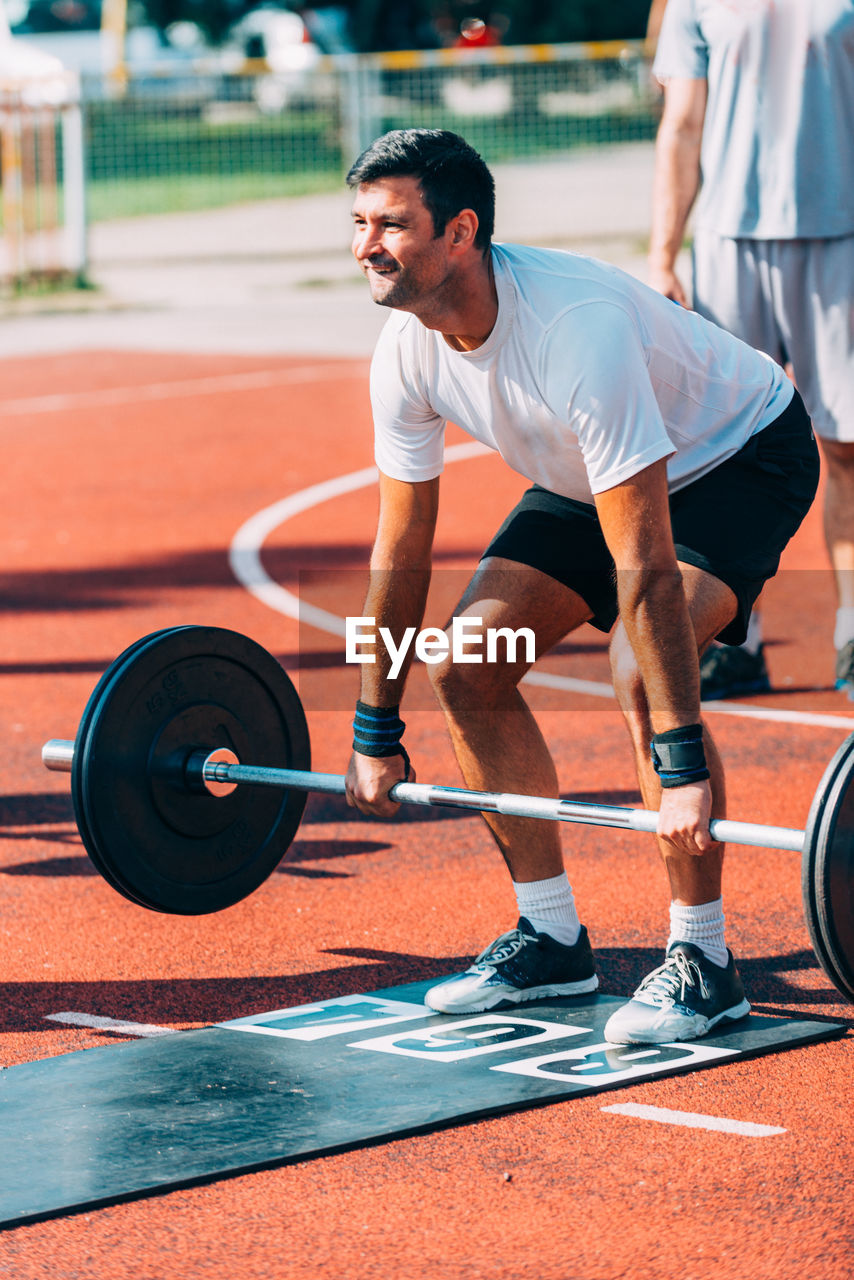 Man lifting dumbbell on running track