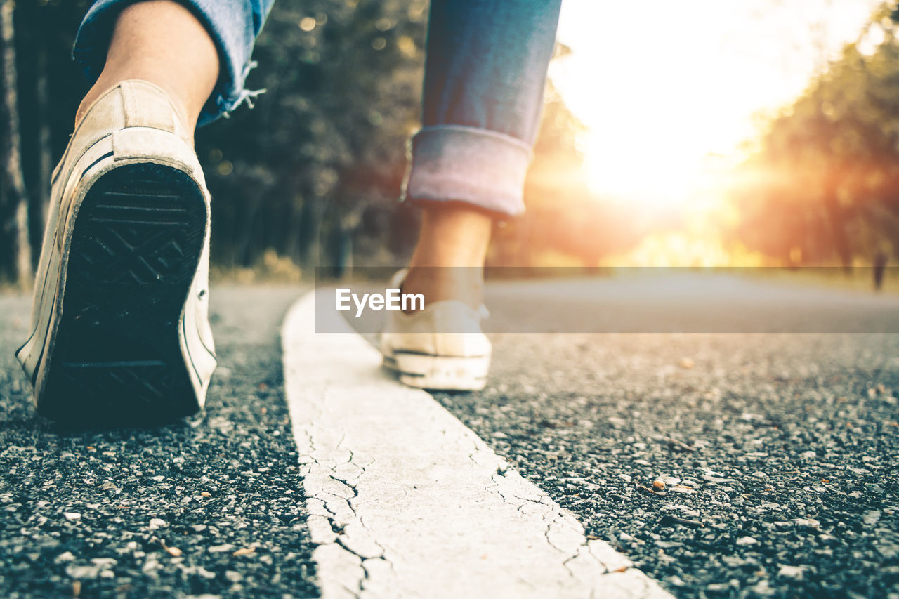 Low section of woman walking on road