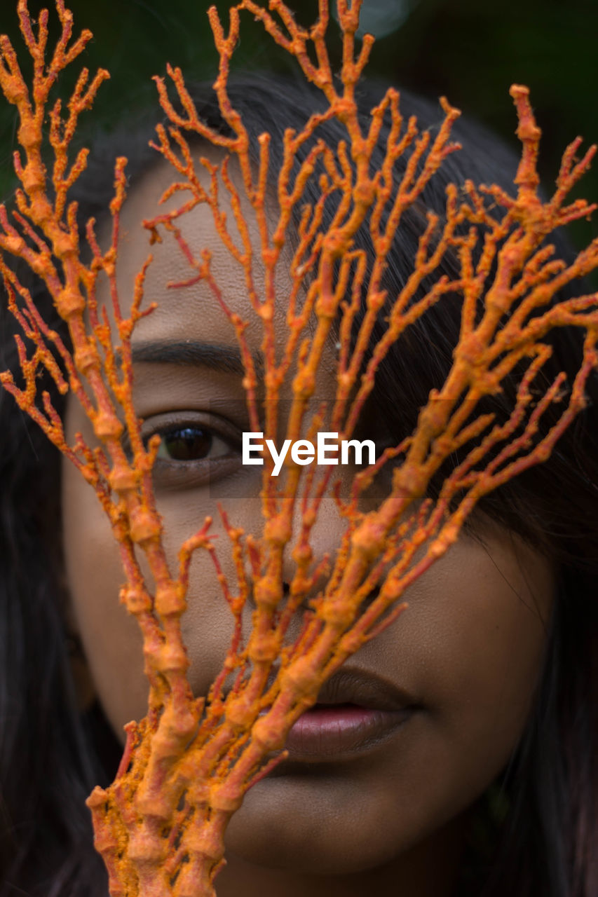 Close-up portrait of a young woman with  orange seaweed 