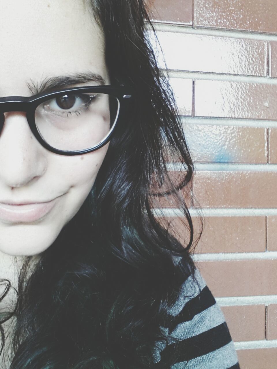 Cropped portrait of young woman wearing eyeglasses by wall