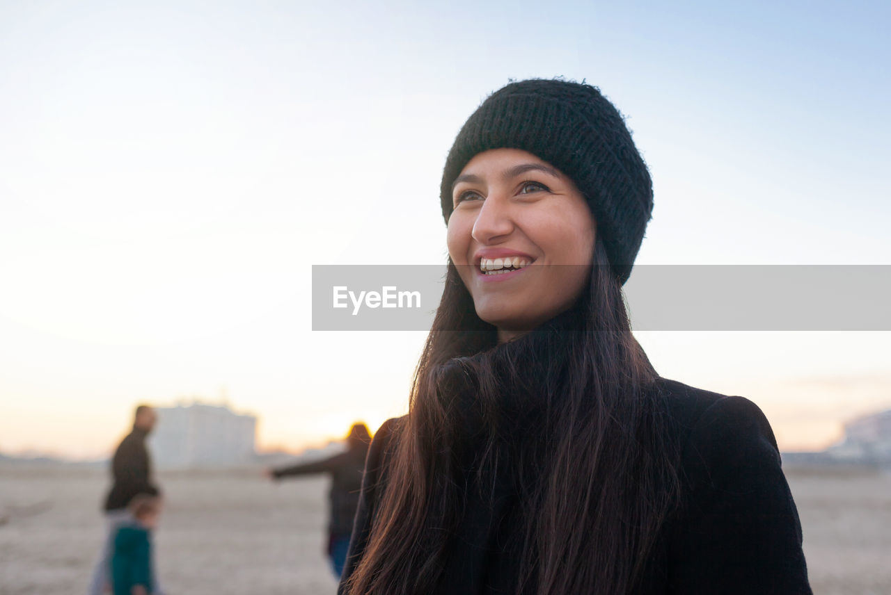 Close-up of smiling young woman against sky