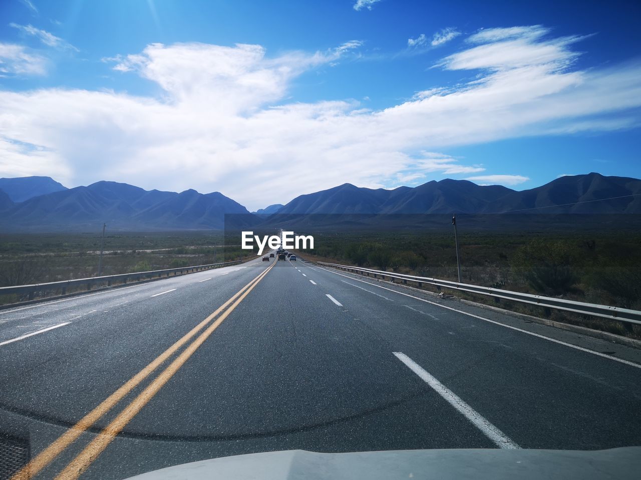 empty road by mountains against sky