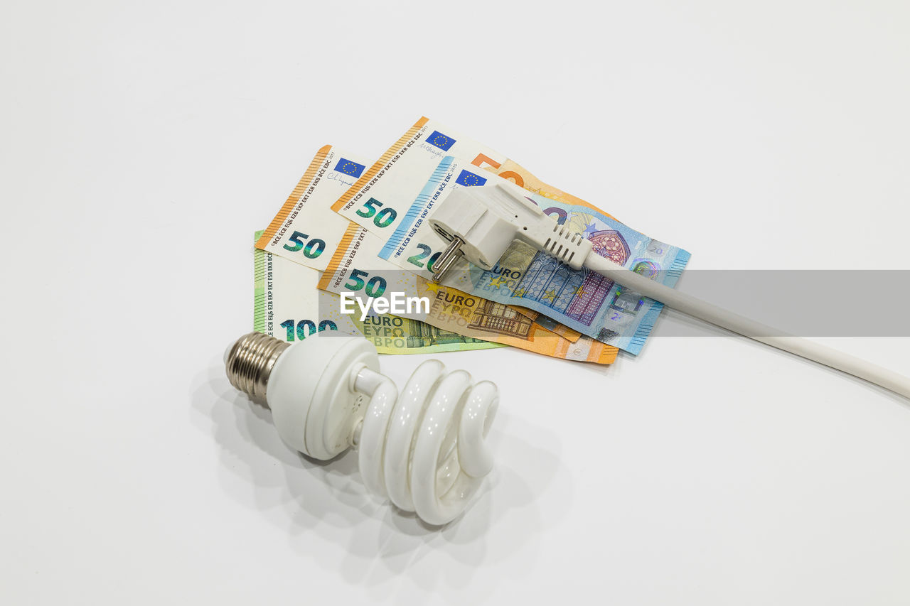 Electric plug, light bulb, and the euro money banknotes. concept of rising electricity prices